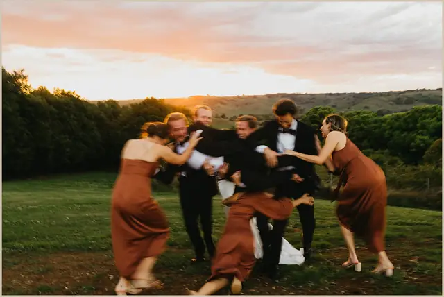 Jess & Rich at The Orchard Estate: The wedding party laugh together in the sunset light.