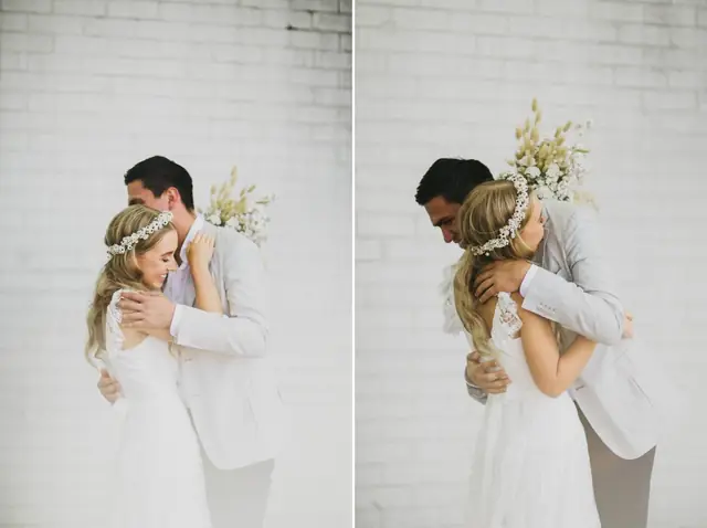 Tali & Jesse at Three Blue Ducks: The couple embrace against a white brick wall.
