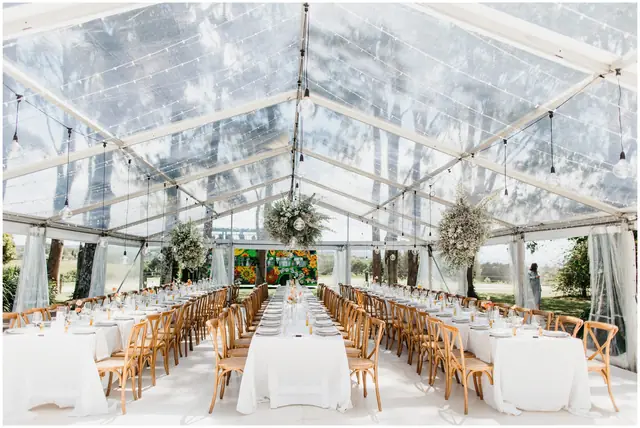 Marty & Nicola at Byron View Farm: Long reception tables beneath a clear marquee and hanging lights.