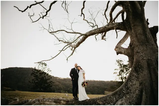 Luke & Cara at Cowbell Creek: The couple embrace beneath a tall, spreading tree.