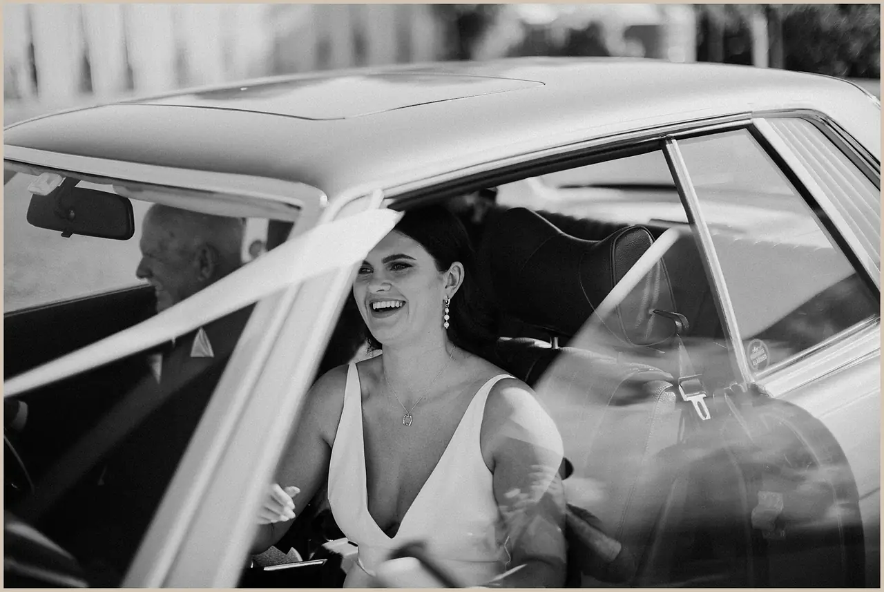 Jess & Rich at The Orchard Estate: The bride smiles from inside the wedding car.