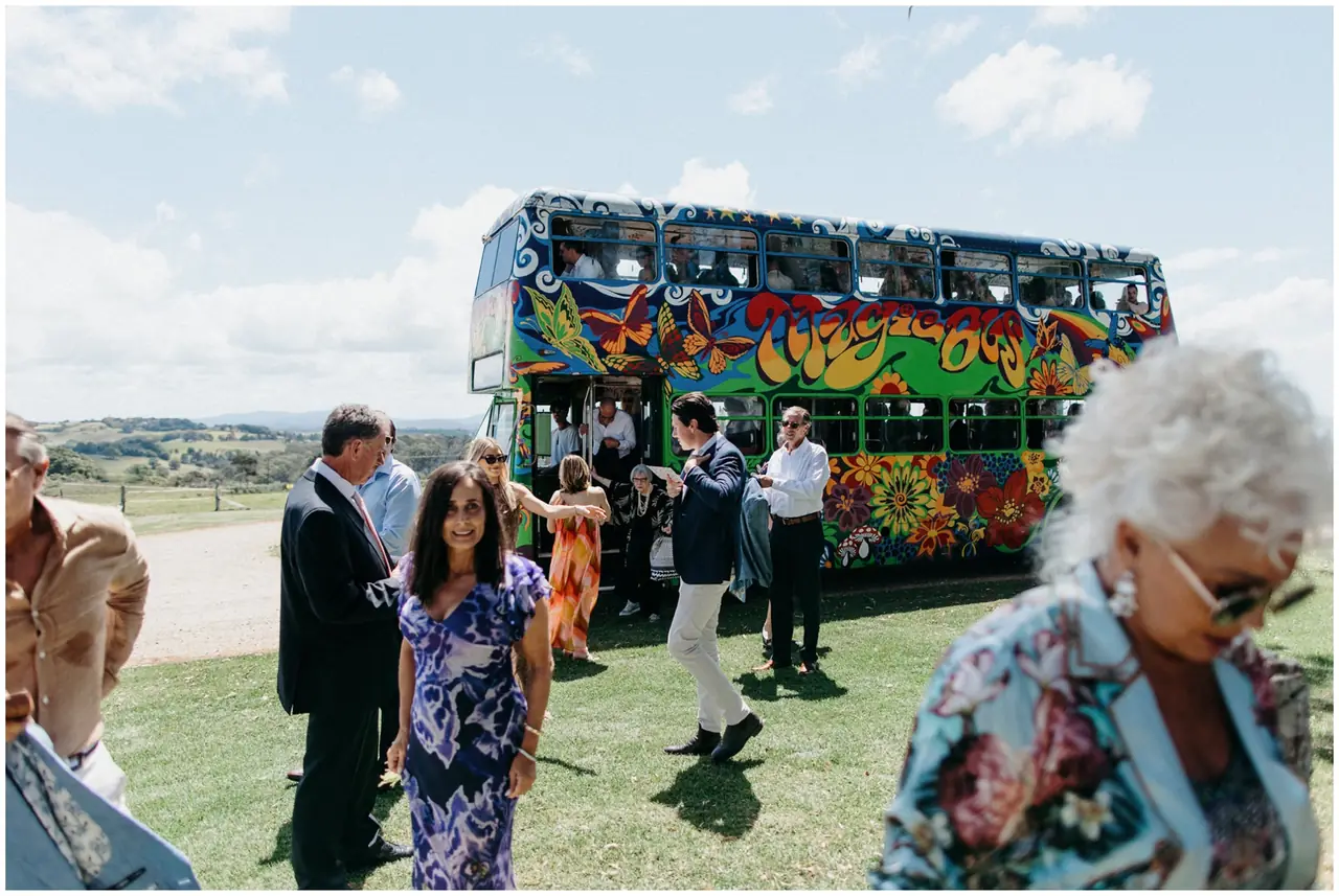 Marty & Nicola at Byron View Farm: Wedding guests gather beside a brightly painted bus.
