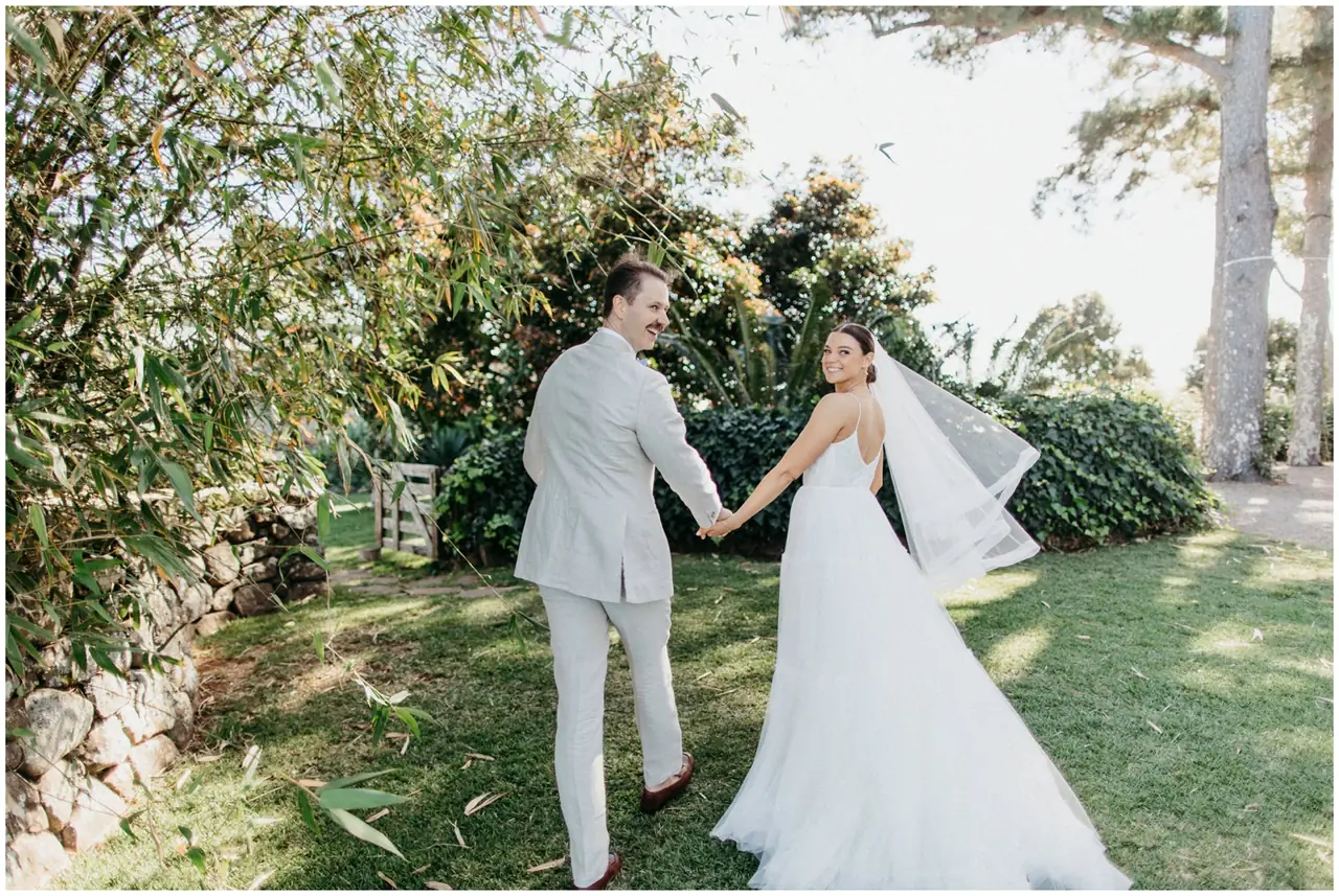 Marty & Nicola at Byron View Farm: The couple hold hands beneath the trees.