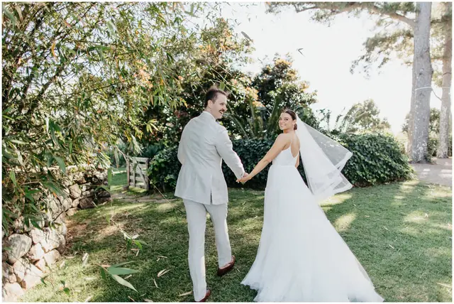 Marty & Nicola at Byron View Farm: The couple hold hands beneath the trees.