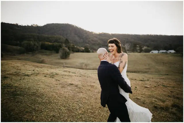 Luke & Cara at Cowbell Creek: The groom lifts the smiling bride in a paddock.