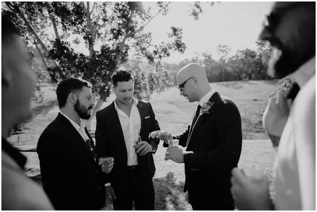 Luke & Cara at Cowbell Creek: The groom talks with friends beneath the trees.