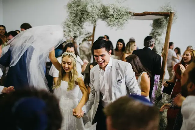 Tali & Jesse at Three Blue Ducks: The newlyweds emerge smiling through a crowd of guests.
