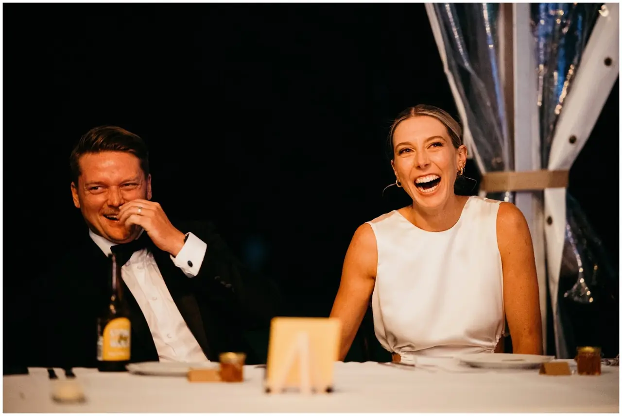 Ella & Jackson at The Woods: The newlyweds laugh together at their reception table.