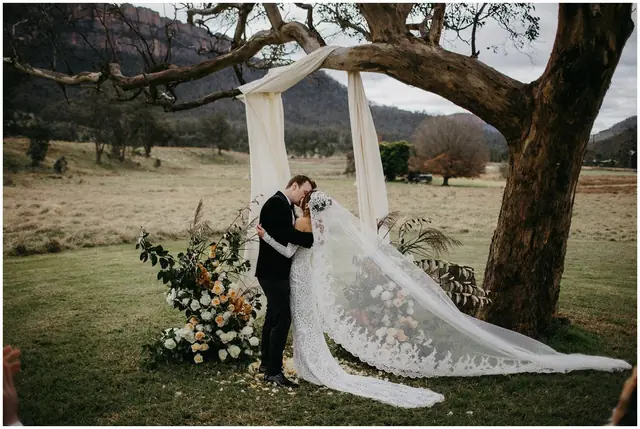 Tom & Josslyn at Emirates One&Only Wolgan Valley: The couple share a kiss beneath the tree and draped fabric.