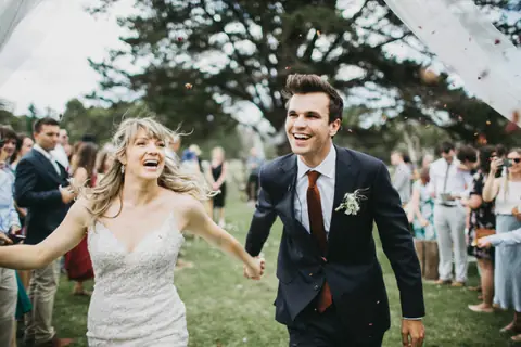 Newlyweds laugh as they walk back through their guests after the ceremony.